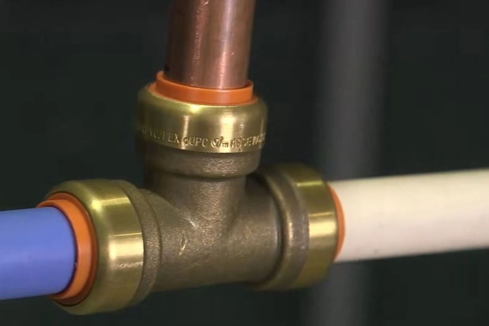 Copper pipe joined to plastic supply pipe with a brass push-fit tee after a repair