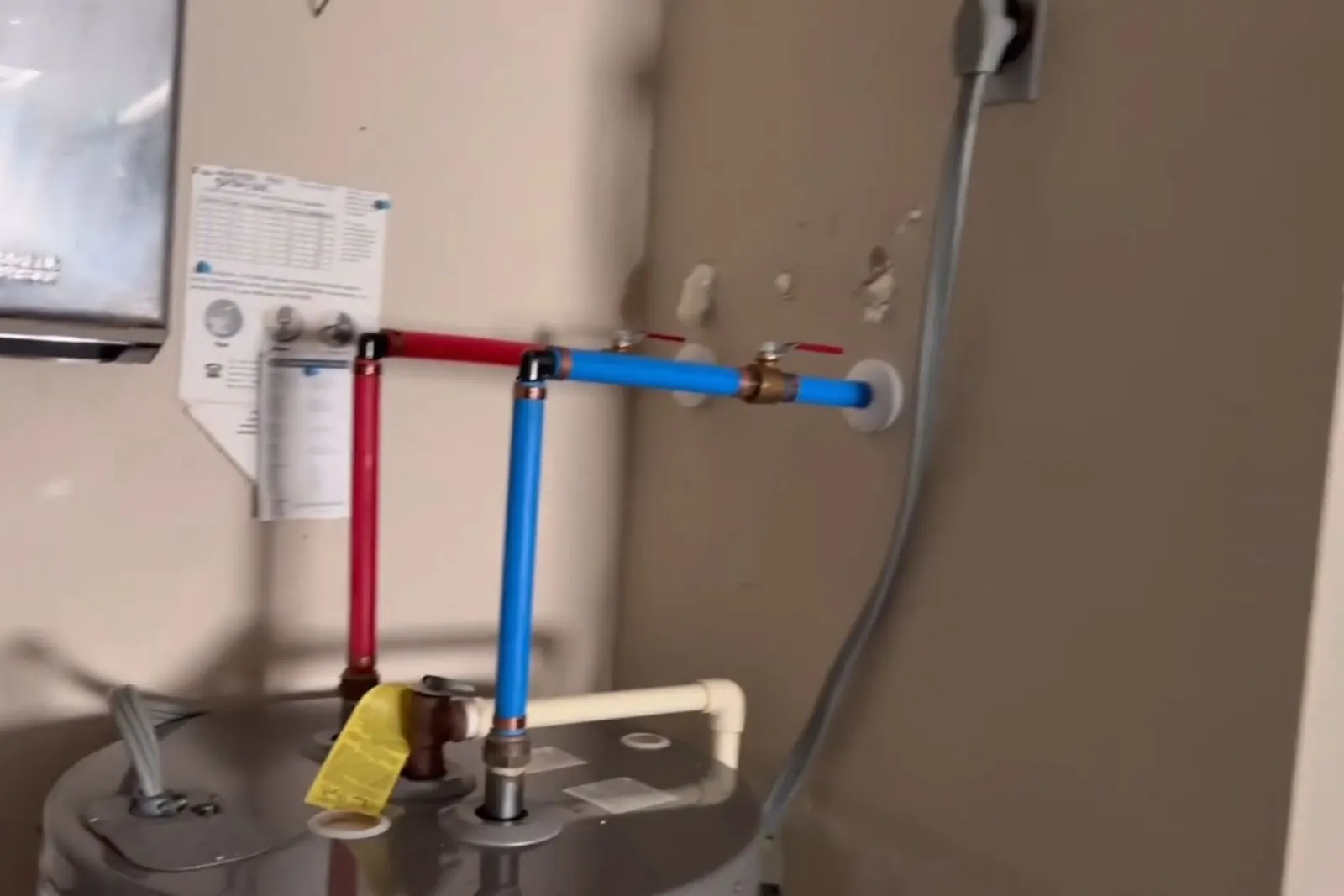 New red and blue PEX lines connected at a wall-mounted water heater
